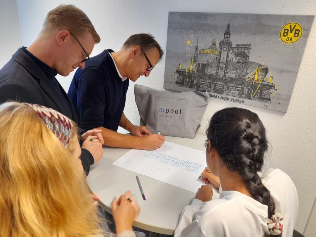 4 Personen unterschreiben ein Plakat