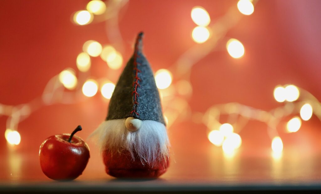 Ein Wichtel und ein Apfel vor einer Lichterkette